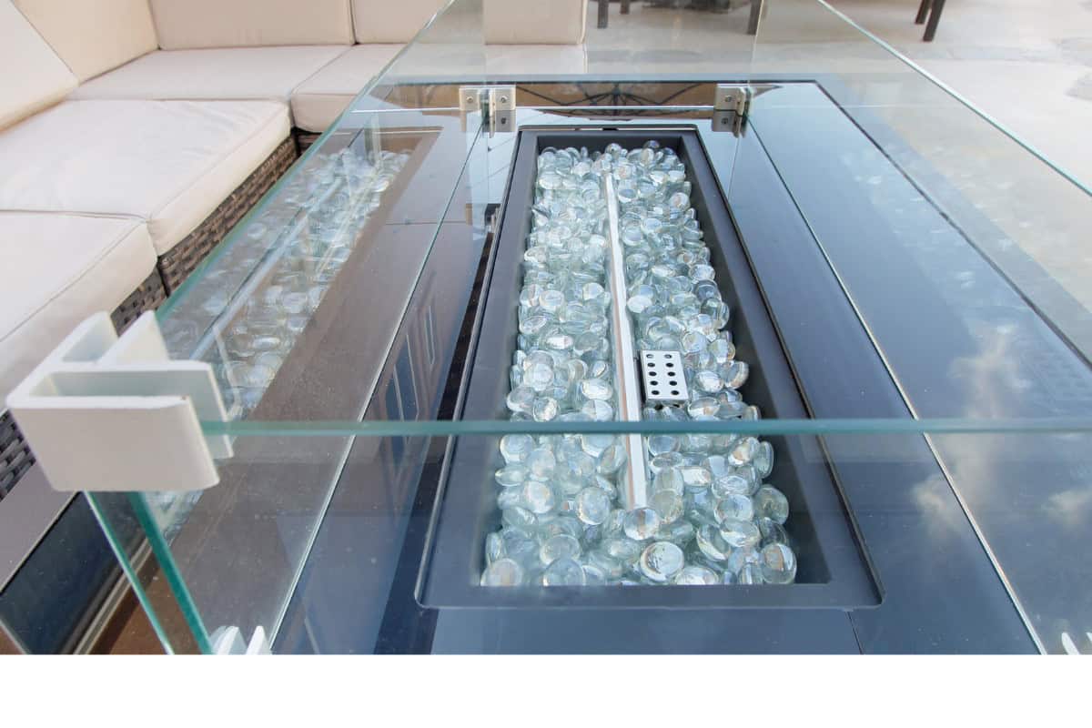 how-much-fire-glass-for-fire-pit-main Image of a rectangular gas fire pit with clear fire glass for a blog post